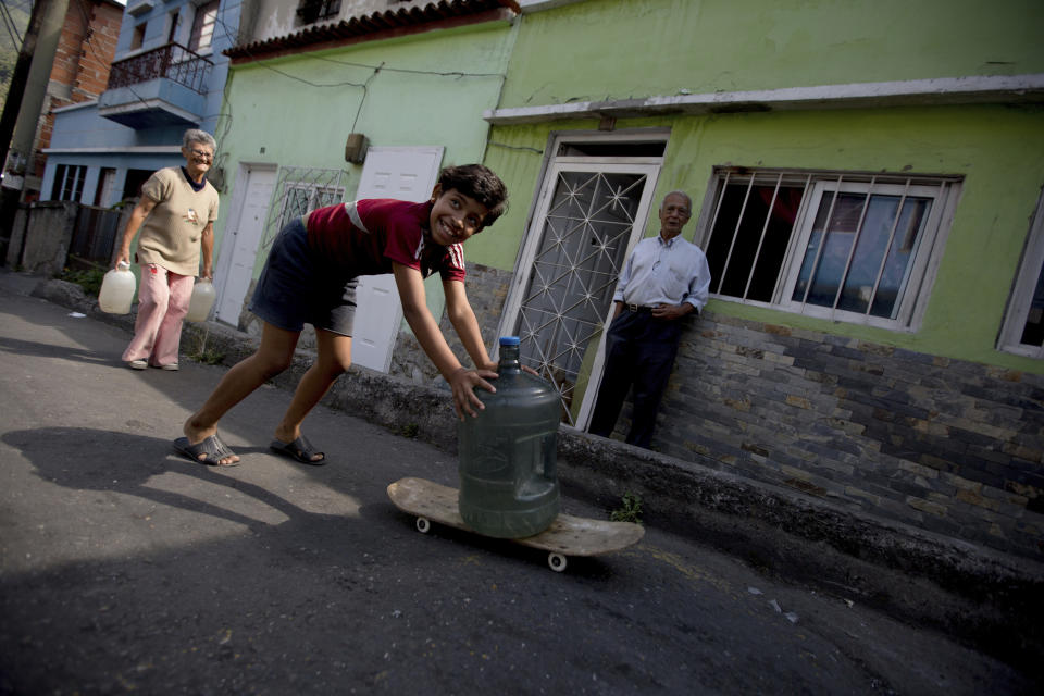 Cotiza neighborhood residents carry water from a public fountain a day after isolated protest against Venezuela's President Nicolas Maduro, in Caracas, Venezuela, Tuesday, Jan. 22, 2019. Working class neighborhoods in Venezuela's capital sifted through charred rubble and smoldering trash on Tuesday, following a day of violence erupting in the streets. (AP Photo/Fernando Llano)