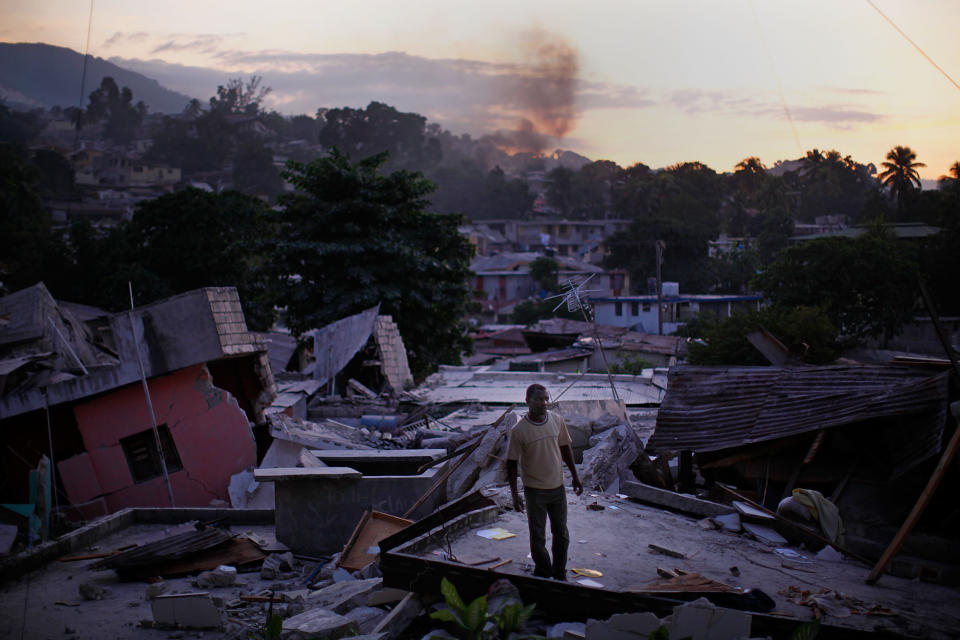 After Haiti's earthquake, a man stands on a rooftop yelling out for any sign of life from his missing relatives in a Port-au-Prince neighborhood.