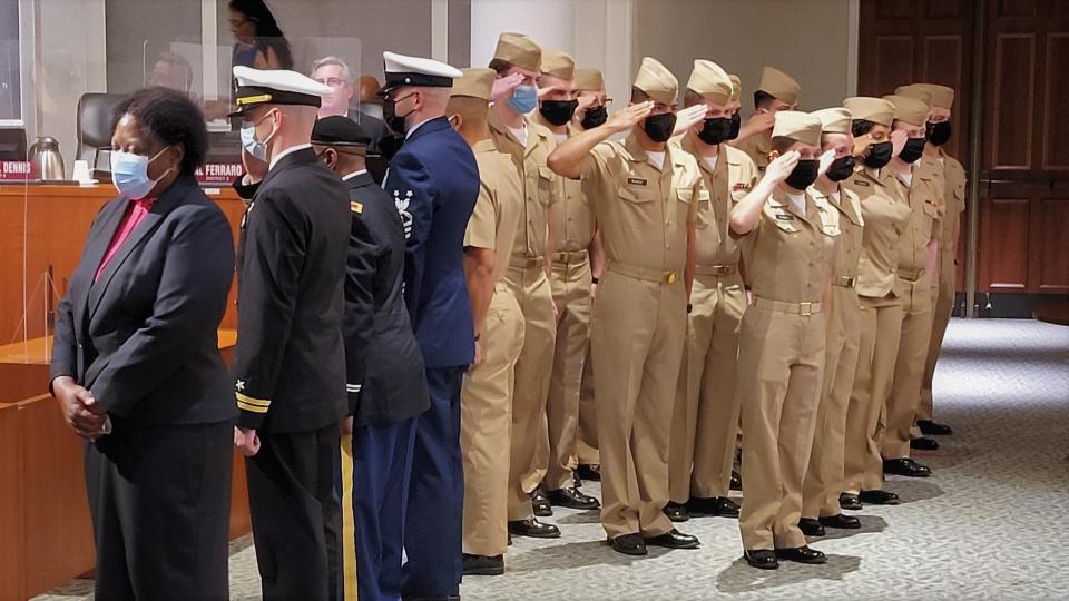 Midshipmen from Jacksonville University's NROTC program salute, as do members of other armed forces as Cynthia Byrd Conner (left) receives Councilwoman Ju'Coby Pittman's resolution honoring her late father, Master Chief Boatswain’s Mate Sherman Byrd, at Tuesday's council meeting.