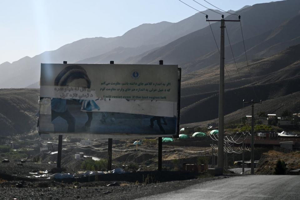 A destroyed poster depicts the late Afghan Mujahideen leader Ahmad Shah Massoud alongside a message about resistance, on a roadside near Dashtak in Panjshir province (AFP via Getty)