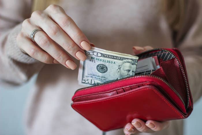 A woman holding a red wallet with cash