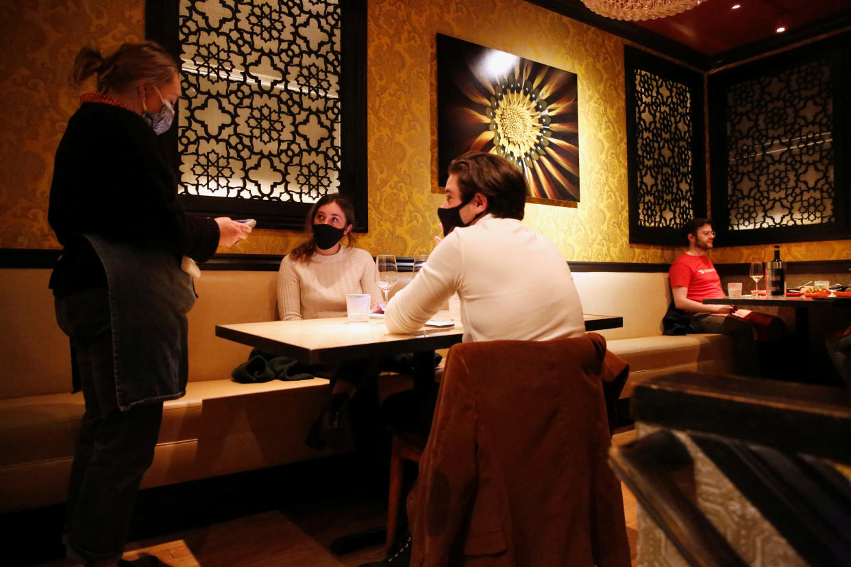 Emily Holloway, 24, and Brian Sussman, 23, speak with server Mikaela Arehart, 28, as they enjoy dinner at an indoor table at Canela Bistro and Wine Bar as indoor dining in the Bay Area resumes after being closed for months due to coronavirus disease (COVID-19) restrictions in San Francisco, California, U.S. March 5, 2021. Picture taken March 5, 2021. REUTERS/Brittany Hosea-Small u000d