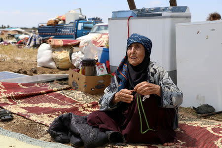 An Internally displaced woman from Deraa province sits near her belongings near the Israeli-occupied Golan Heights in Quneitra, Syria June 29, 2018. REUTERS/Alaa Al-Faqir