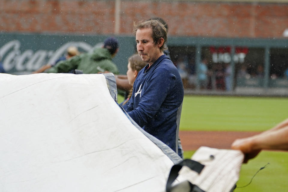 Members of the Atlanta Braves grounds crew work to cover the infield before a baseball game between Atlanta Braves and Colorado Rockies was cancelled because of rain Thursday, Sept. 16, 2021, in Atlanta. (AP Photo/John Bazemore)