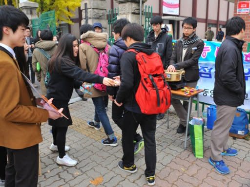 Junior high school students hand out sweets as the seniors arrive for their college entrance examination at a school in Seoul, on November 8. Military training was suspended and flights rescheduled as some 668,500 students took the standardised College Scholastic Ability Test nationwide