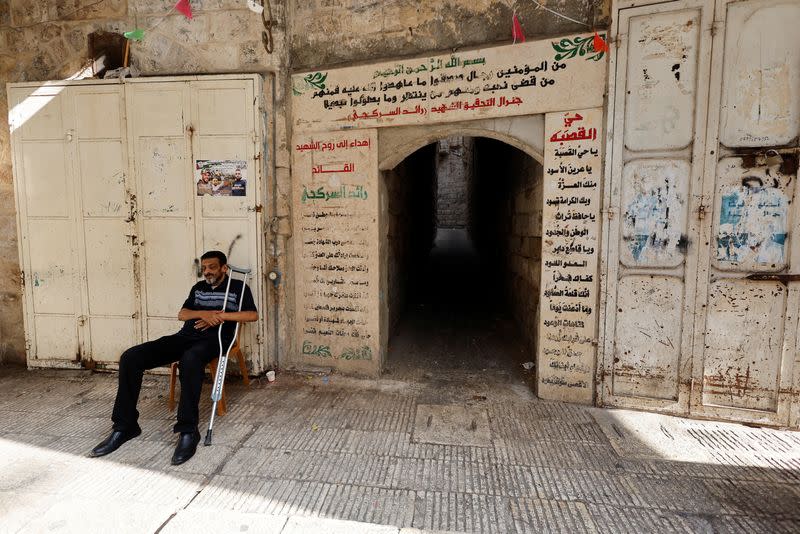 A man sits in front of a closed shop, during a general strike, after Palestinian Den of Lions member Tamer Kilani was killed in an explosion, in Nablus