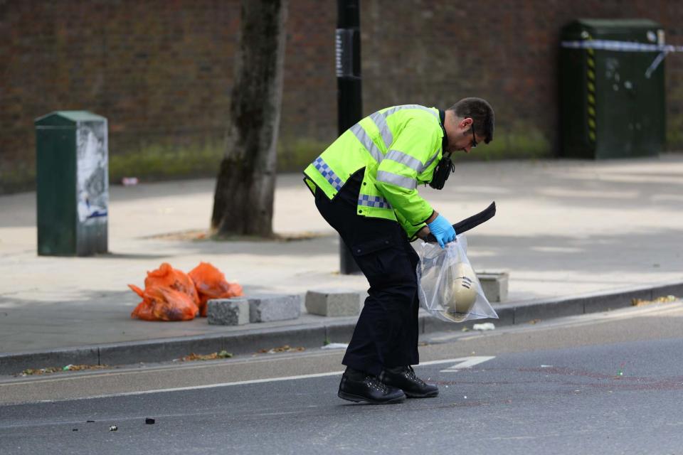 Police at the scene in Battersea, south-west London, where a woman in her 30s died after being struck by a lorry while riding a scooter. (PA)