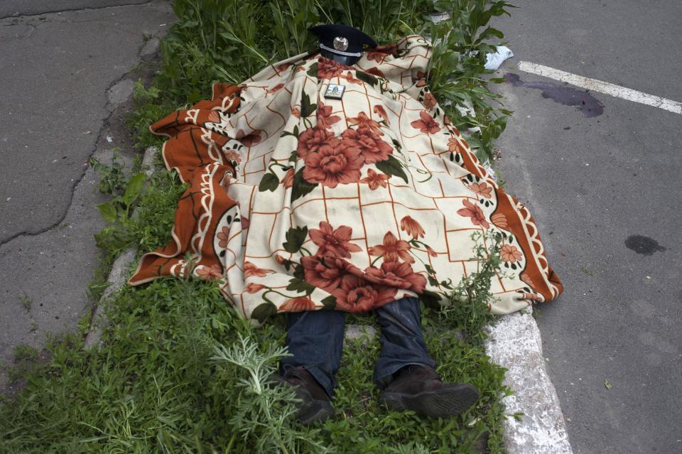 The body of a police officer lies outside a police station in Mariupol, eastern Ukraine, Friday, May 9, 2014. Fighting between government forces and insurgents in Mariupol has left several people dead. (AP Photo/Evgeniy Maloletka)