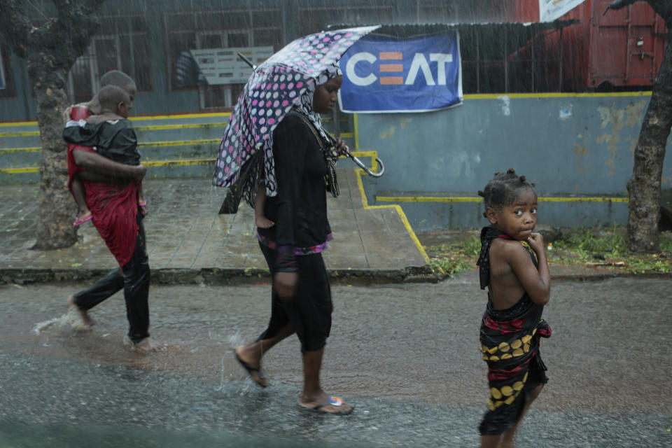 A family walks in the rain, in Natite neighbourhood, Pemba, on the northeastern coast of Mozambique, Sunday, April, 28, 2019. Serious flooding began on Sunday in parts of northern Mozambique that were hit by Cyclone Kenneth three days ago, with waters waist-high in areas, after the government urged many people to immediately seek higher ground. Hundreds of thousands of people were at risk. (AP Photo/Tsvangirayi Mukwazhi)