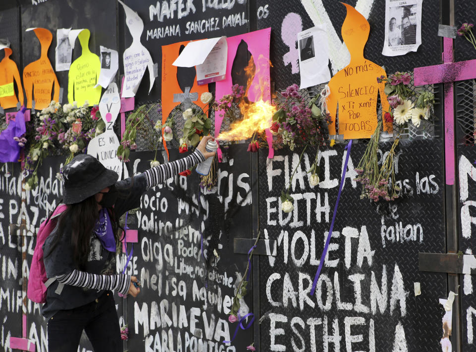 A demonstrator throws fire with a spray can at the police who are behind a barricade that is protecting the National Palace during a march to commemorate International Women's Day and protest against gender violence, in Mexico City, Monday, March 8, 2021. (AP Photo/Ginnette Riquelme)