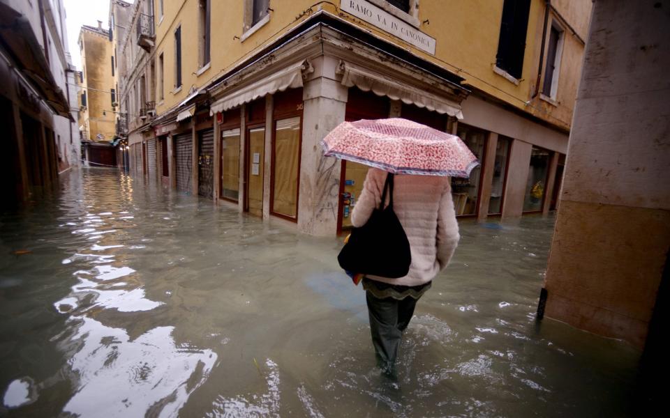 A woman walks through flooded streets in Venice  - Filippo Monteforte/AFP