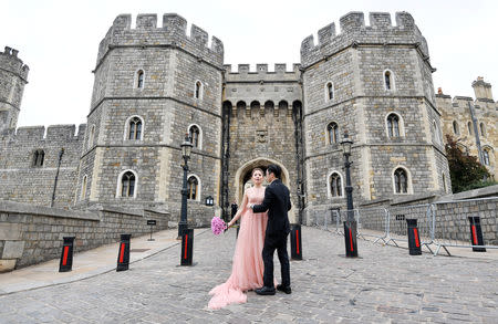 A couple pose for wedding photographs outside Windsor Castle a day ahead of the royal wedding between Princess Eugenie and Jack Brooksbank in Windsor, Britain, October 11, 2018. REUTERS/Toby Melville