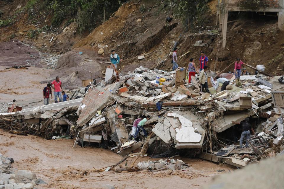 La gente camina sobre los escombros de un edificio derrumbado en Mocoa, Colombia, el domingo 2 de abril de 2017. El presidente Juan Manuel Santos, quien declaró a Mocoa una zona de desastre, dijo que al menos 207 personas murieron pero que la cifra cambia a "cada momento". (AP Foto/Fernando Vergara)