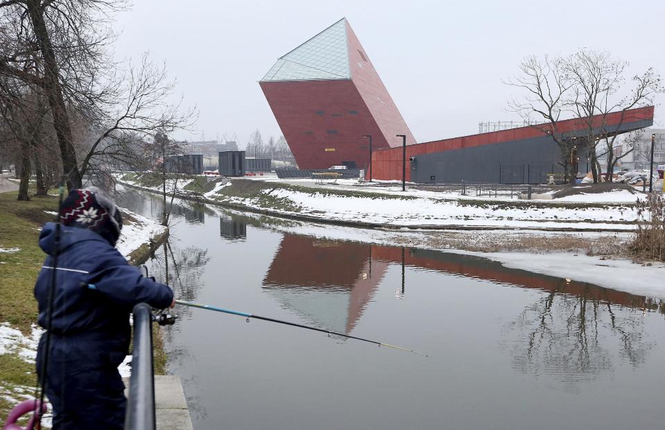 A woman fishes near the Museum of the Second World War, an ambitious new museum under creation for nine years which is almost completed, in Gdansk, Poland, on Monday, Jan. 23, 2017. (AP Photo/Czarek Sokolowski)