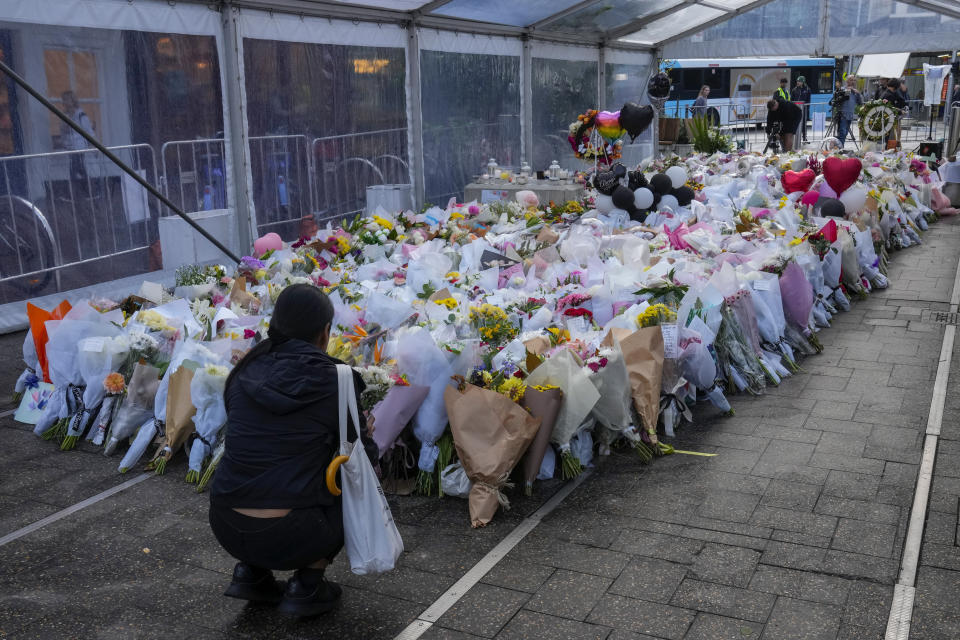 A woman lays flowers at a tribute for the victims of Saturday's knife attack near a crime scene at Bondi Junction in Sydney, Thursday, April 18, 2024. A Sydney shopping mall has been opened to the public for the first time since it became the scene of a mass stabbing in which six people died, while the Australian prime minister has flagged giving citizenship to an immigrant security guard who was injured while confronting the knife-wielding attacker. (AP Photo/Mark Baker)