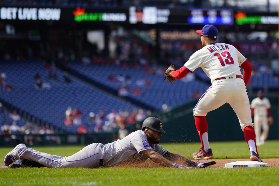 Colorado Rockies' Elias Diaz, left, slides into first base for a single past Philadelphia Phillies first baseman Brad Miller during the seventh inning of a baseball game, Sunday, Sept. 12, 2021, in Philadelphia. (AP Photo/Matt Slocum)