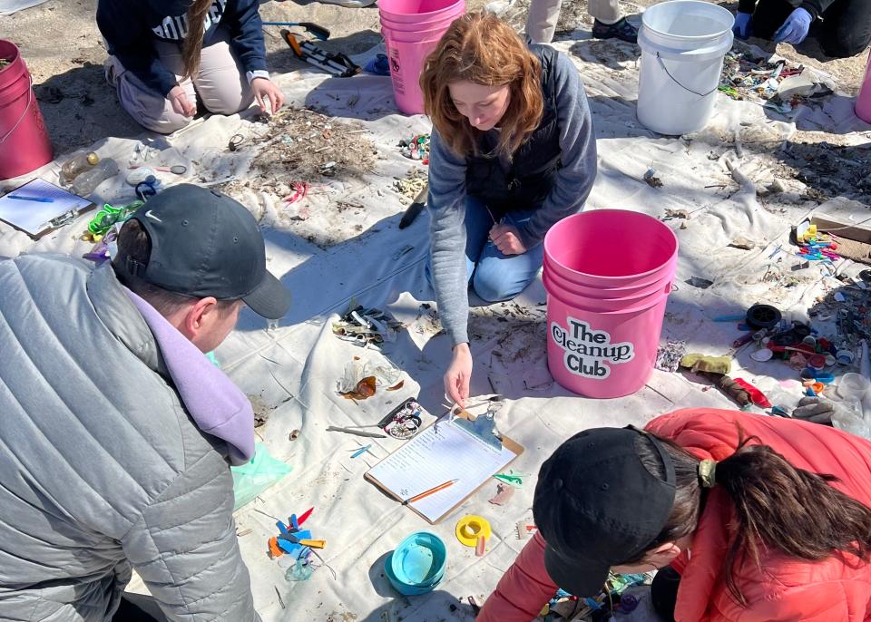 Volunteers of The Cleanup Club, Evan Theys, left, Hannah Craik and Claire Mahler count and categorize beach cleanup finds for research and advocacy efforts.