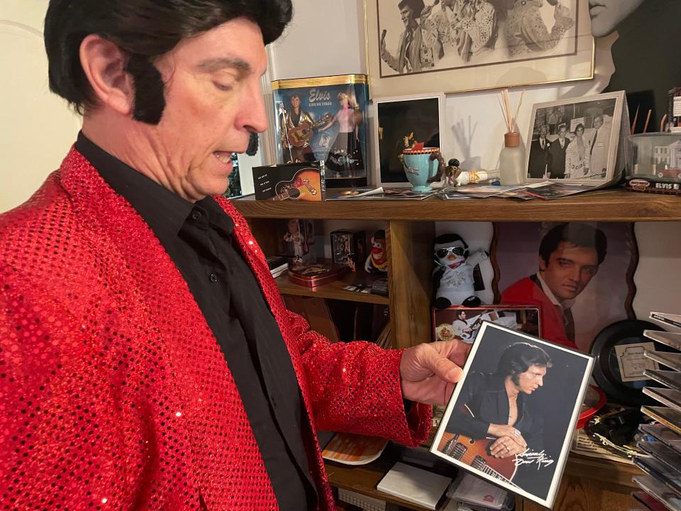 Dave "King" Falzetti studies a photograph of a younger version of his Elvis self, Tuesday, Dec. 20, 2022. Falzetti is going for a Guinness World Record.