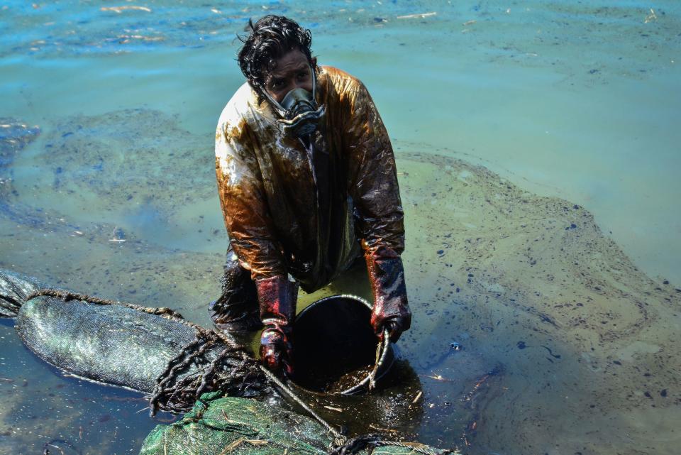 A man scoops leaked oil from the vessel MV Wakashio off the coast of south-east Mauritius.