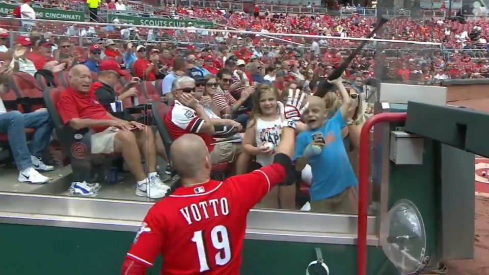 Joey Votto handing his bat to 6-year-old cancer patient Walter “SuperBubz” Herbert. (MLB.com)