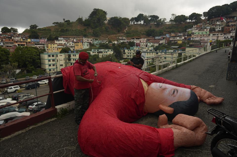 Supporters of Venezuela's late President Hugo Chavez bring down an inflatable doll of Chavez during a commemoration of what would have been the leader's 68th birthday, at the 23 de Enero neighborhood in Caracas, Venezuela, Thursday, July 28, 2022. (AP Photo/Ariana Cubillos)