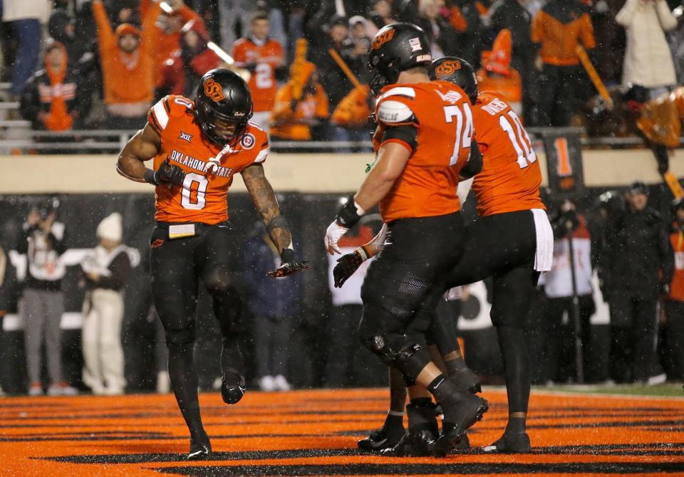 Nov 25, 2023; Stillwater, Oklahoma, USA; Oklahoma State's Ollie Gordon II (0) celebrates with Oklahoma State's Preston Wilson (74) and Rashod Owens (10) after scoring a touchdown during the second overtime against the Brigham Young Cougars at Boone Pickens Stadium. Mandatory Credit: Sarah Phipps-USA TODAY Sports