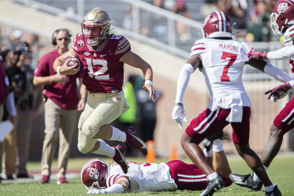 Florida State quarterback Chubba Purdy (12) jumps Massachusetts safety Tanner Davis (3) for a gain in the second half of an NCAA college football game against Massachusetts in Tallahassee, Fla., Saturday, Oct. 23, 2021. Florida State defeated UMass 59-3. (AP Photo/Mark Wallheiser)