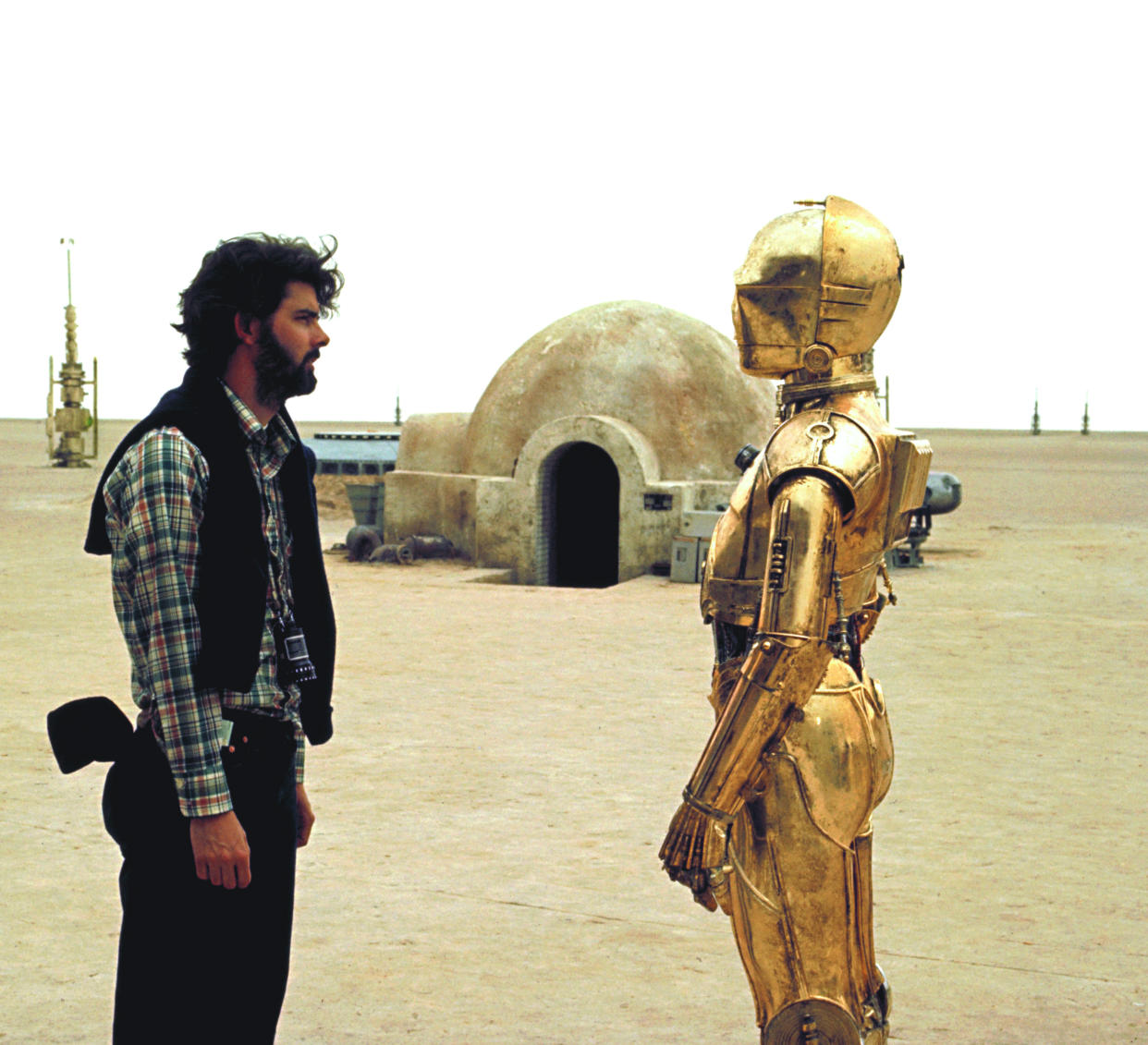 British actor Anthony Daniels (who plays C-3PO) with American director, screenwriter and producer George Lucas on the set of his movie Star Wars: Episode IV - A New Hope. (Photo by Sunset Boulevard/Corbis via Getty Images)