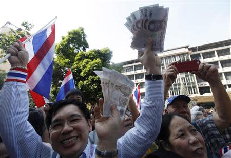 Anti-government protesters hold Thai banknotes to donate to their leader Suthep Thaugsuban during a rally at a major business district in Bangkok December 20, 2013. A REUTERS/Kerek Wongsa