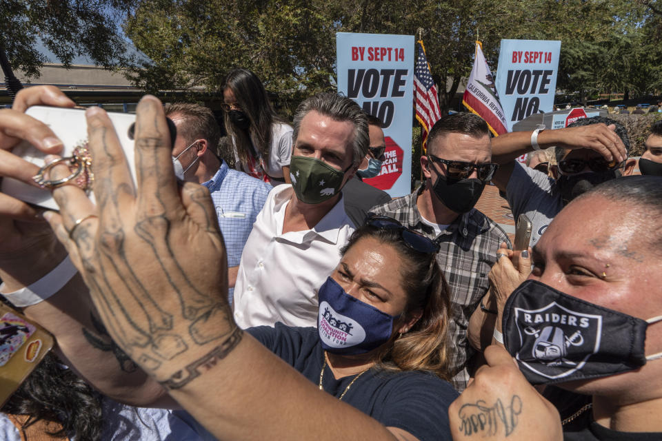 California Gov. Gavin Newsom, middle, takes selfies with supporters at an event against the recall election at the Culver City High School in Culver City, Calif., Saturday, Sept. 4, 2021.