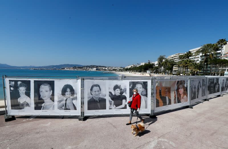 A woman walks past photos of the Cannes Film festival on the Croisette in Cannes as a lockdown is imposed to slow the rate of the coronavirus disease (COVID-19) in France