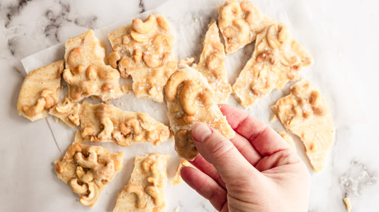 Hand holding a piece of cashew brittle