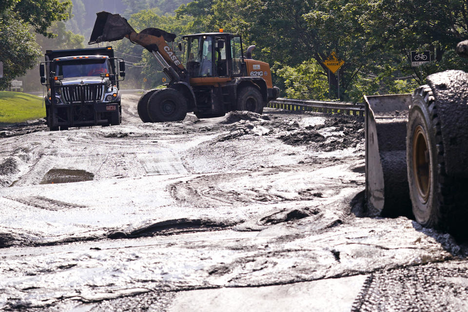 Bucket loaders clear mud from a road leading to downtown, Wednesday, July 12, 2023, in Montpelier, Vt. Following a storm that dumped nearly two months of rain in two days, Vermonters are cleaning up from the deluge of water. (AP Photo/Charles Krupa)