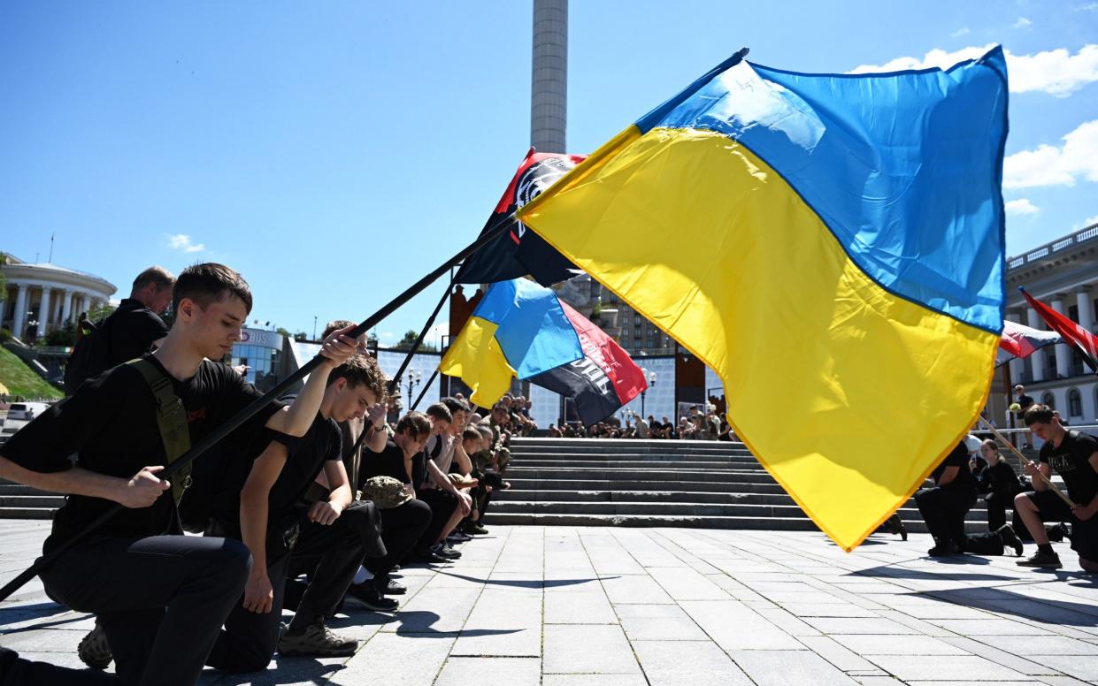 People kneel during a funeral ceremony in Kyiv for Peter Fouche, a British volunteer