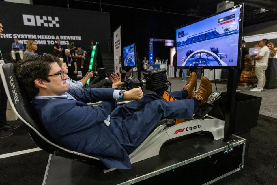 A person tries a sports car driving simulator in a trade show booth at eMerge Americas conference on April 20, 2023.