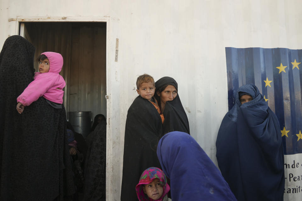 Afghan women gather outside a makeshift clinic organized by World Vision at a settlement near Herat, Afghanistan, Dec. 16, 2021. The aid-dependent country’s economy was already teetering when the Taliban seized power in mid-August amid a chaotic withdrawal of U.S. and NATO troops. The consequences have been devastating for a country battered by four decades of war, a punishing drought and the coronavirus pandemic. (AP Photo/Mstyslav Chernov)