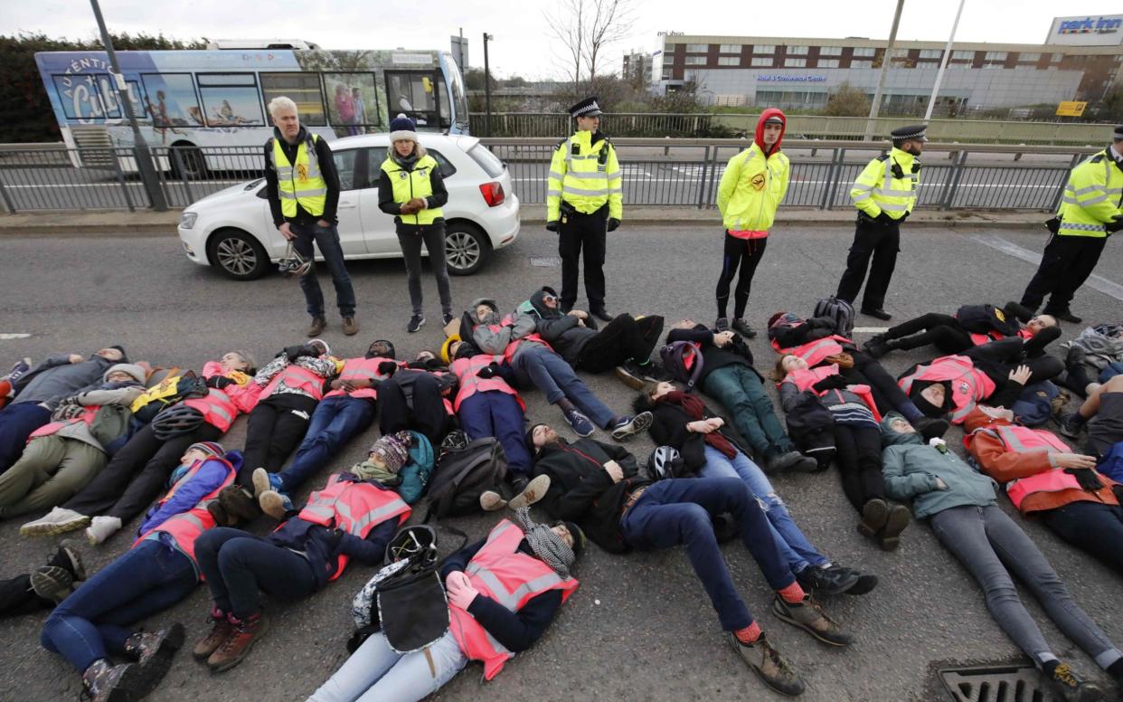 Activists from climate action group Extinction Rebellion perform a symbolic 'bulldozer lie-in' as they demonstrate against the building of a third runway at Heathrow Airport - AFP