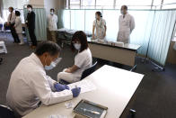 A medical worker checks the form of his colleague before giving her a dose of the COVID-19 vaccine at Tokyo Medical Center in Tokyo Wednesday, Feb. 17, 2021. Some wealthy nations that were most praised last year for controlling the coronavirus are now lagging far behind in getting their people vaccinated — and some, especially in Asia, are seeing COVID-19 cases grow. (Behrouz Mehri/Pool Photo via AP)