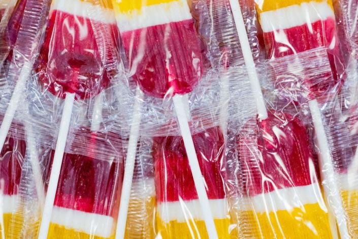 Pink, white, and yellow striped lollipops in plastic wrappers.