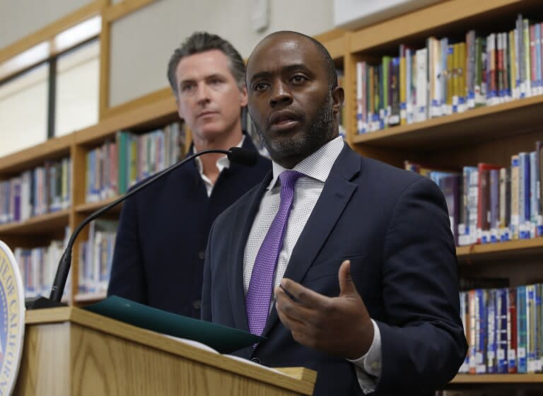 FILE — In this Oct. 31, 2019, file photo, state Superintendent of Public Instruction Tony Thurmond answers a reporter's question during a visit with Gov, Gavin Newsom, background, to Blue Oak Elementary School, in Cameron Park, Calif. Thurmond said on Wednesday, April 29, 2020, that California schools won't reopen until it can be done safely, due to the new coronavirus pandemic. (AP Photo/Rich Pedroncelli, File)