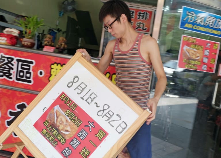 Carlos Cheung, 28, a Hong Kong emigrant to Taiwan, places a sign in front of his food stall in central Taichung