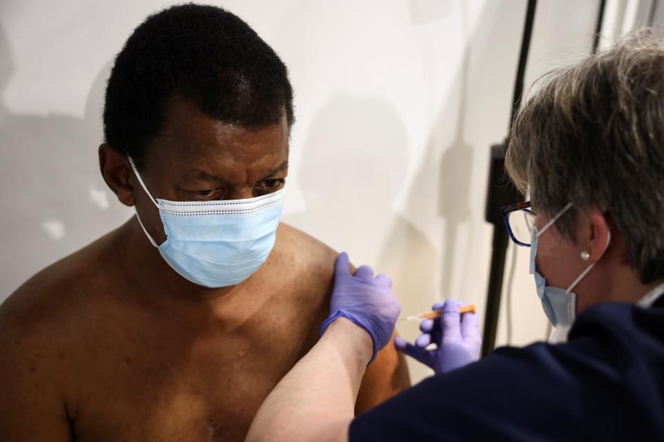 <p>A person gets the coronavirus vaccine, at a vaccination centre in Westfield Stratford City shopping centre</p> (Reuters)