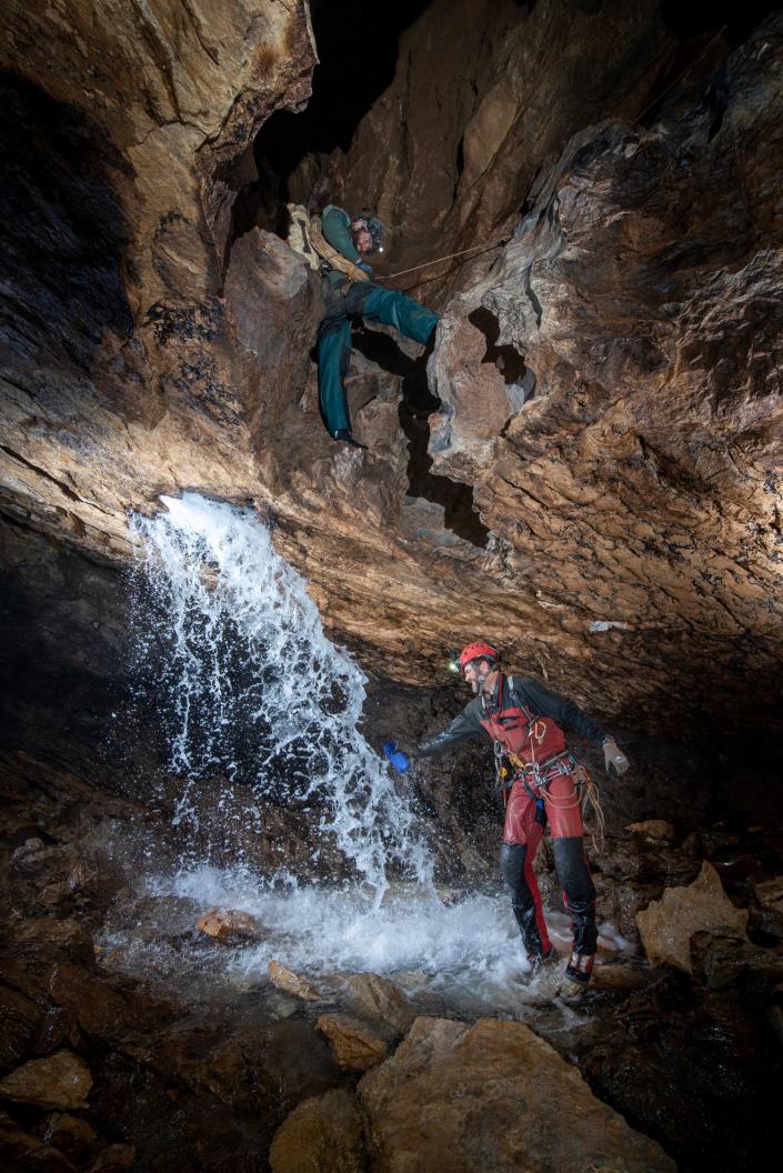 caver fills up a bottle of water from a waterfall inside a cave system