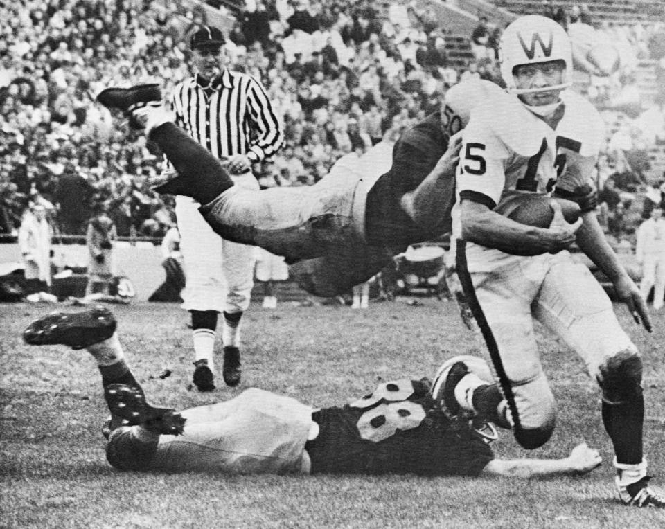 FILE - Illinois' Dick Butkus, top, and Rich Callaghan, bottom, try to tackle Wisconsin quarterback Ron Vanderkelen (15) during the second quarter of an NCAA college football game Nov. 17, 1962, in Champaign, Ill. Butkus, a fearsome middle linebacker for the Chicago Bears, has died, the team announced Thursday, Oct. 5, 2023. He was 80. According to a statement released by the team, Butkus' family confirmed that he died in his sleep overnight at his home in Malibu, Calif. (AP Photo/Larry Stoddard, File)