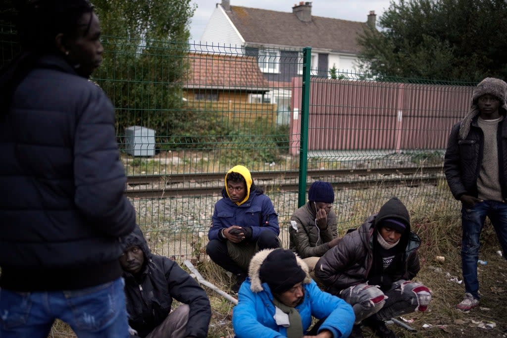 Migrants and refugees wait for food distribution at a camp in Calais (AP)