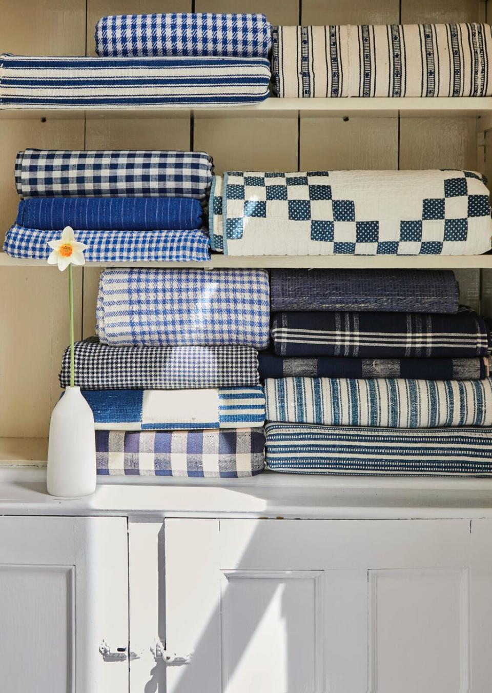 a shelf with blue and white quilts and blankets