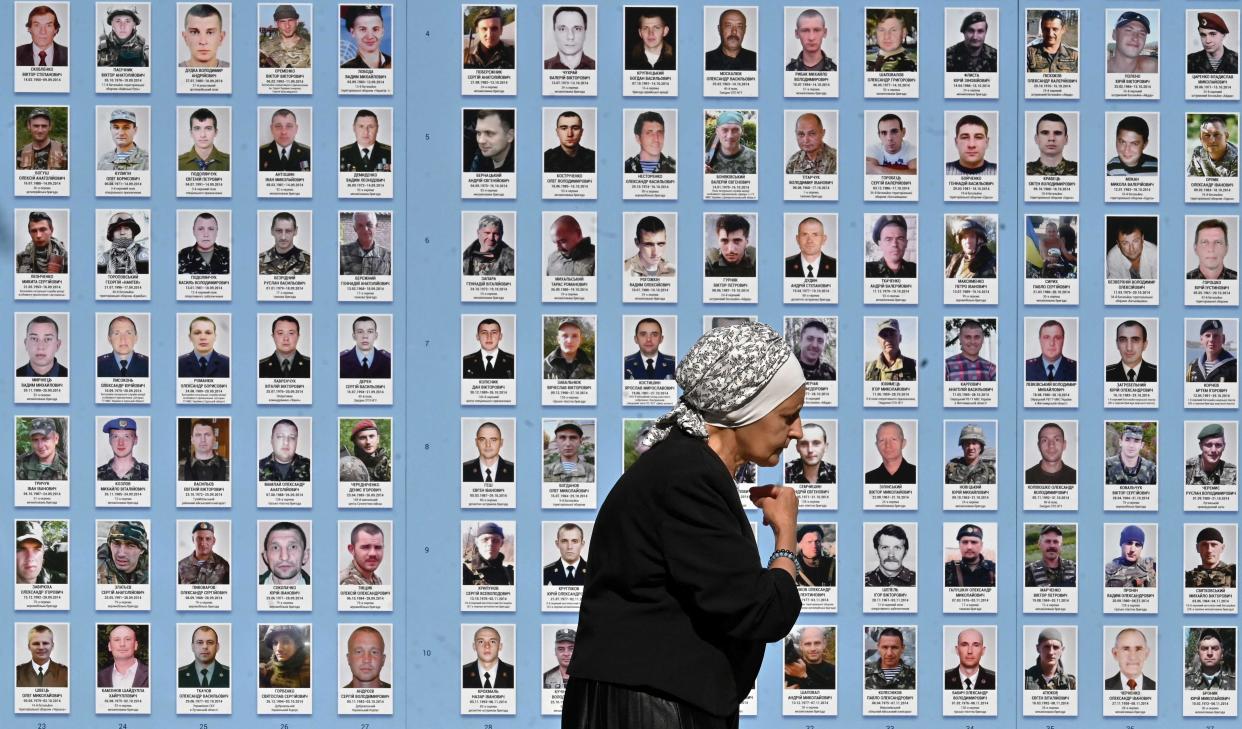 An elderly woman crosses herself as she walks past the Memory Wall of Fallen Defenders of Ukraine today (AFP via Getty Images)