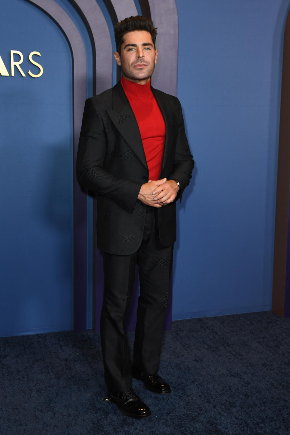 Zac Efron in a red turtleneck and black suit at the honourary Oscars. (Image via Getty Imags)