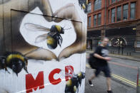 <p>A man walks past graffiti on a wall depicting bees in Manchester, Sunday, May 28, 2017. Manchester residents are getting tattoos of bees to raise money for victim’s of Monday’s terror attack at an Ariana Grande concert. (Photo: Mstyslav Chernov/AP) </p>