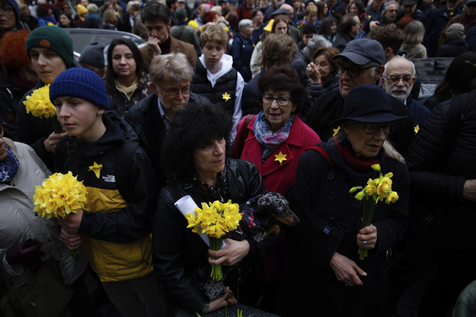 People hold yellow tulips during personal unofficial observances marking the 80th anniversary of the Warsaw Ghetto Uprising in Warsaw, Poland, Wednesday, April 19, 2023. (AP Photo/Michal Dyjuk)